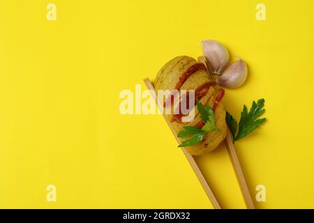 Pinze in legno con patate al forno su sfondo giallo. Foto Stock