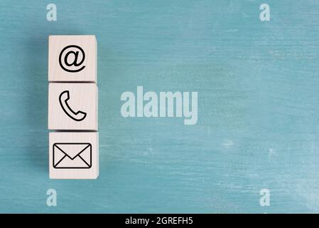 Segni per e-mail, telefono e newsletter su blocchi di legno, sfondo blu, simboli e segni Foto Stock