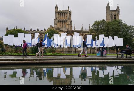 La gente cammina accanto a Luke Jerram's in Memoriam, un'installazione d'arte potente e significativa, creata in memoria delle perdite subite durante la pandemia COVID-19, dopo che è stata installata nel Bristol's College Green. L'installazione, che sarà aperta al pubblico dal 1° al 17 ottobre, è composta da oltre 100 bandiere di lenzuola ospedaliere NHS. Data foto: Venerdì 1 ottobre 2021. Foto Stock