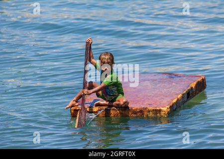 Indonesia, Papua, isola di Biak, ragazzo che gioca con una zattera sul mare Foto Stock