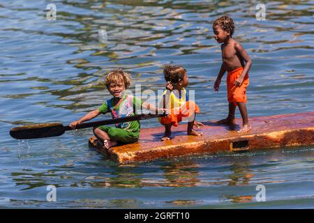 Indonesia, Papua, isola di Biak, ragazzi che giocano con una zattera sul mare Foto Stock