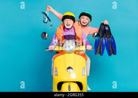 Foto di felice stupito grigio capelli pensionato pensionato coppia indossare casco tenere subacqueo attrezzatura biker isolato su sfondo blu Foto Stock