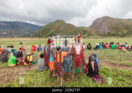 Indonesia, Papua, la città di Wamena, i bambini Dani guardano al sito del festival culturale, di fronte agli stand. Baliem Valley Cultural Festival, ogni agosto, le tribù si riuniscono per eseguire scene di guerra ancestrali, sfilate e danze in abiti tradizionali Foto Stock