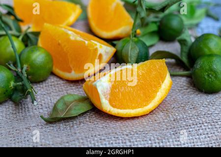 Arance sunkist che sono state tagliate, disposte insieme con lime intere e foglie di lime che hanno cominciato ad asciugare Foto Stock