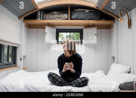 La donna che si gustava un caffè si sedette in una capanna di pastori nelle Cotswolds Foto Stock