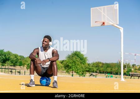 giocatore di basket che ascolta musica con il suo smartphone Foto Stock