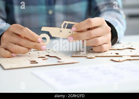 Le mani femminili assemblano l'automobile del giocattolo di legno dalle parti differenti Foto Stock