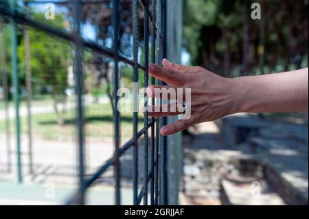 Signora che tiene alle sbarre con le mani Foto Stock