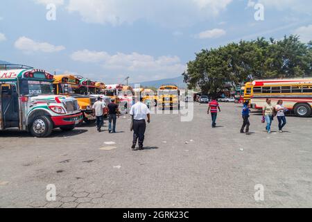 ANTIGUA, GUATEMALA - 28 MARZO 2016: I colorati autobus di pollo, ex autobus scolastici statunitensi, sono allineati al terminal principale degli autobus nella città di Antigua Guatemala. Foto Stock