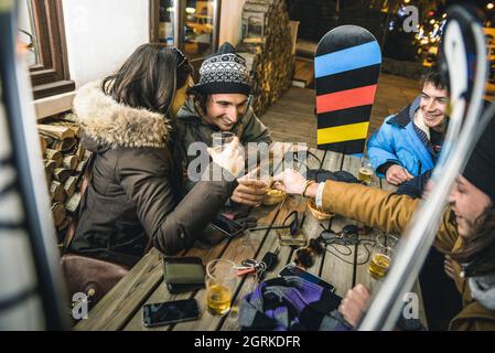 Amici felici che bevono birra e mangiano patatine all'Apres Ski - concetto di amicizia con gente allegra che si diverte al bar ristorante resort Foto Stock