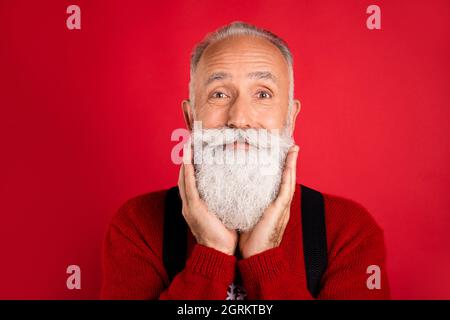 Foto di uomo maturo felice sorriso positivo mani toccare barba barbiere cura negozio isolato su sfondo di colore rosso Foto Stock