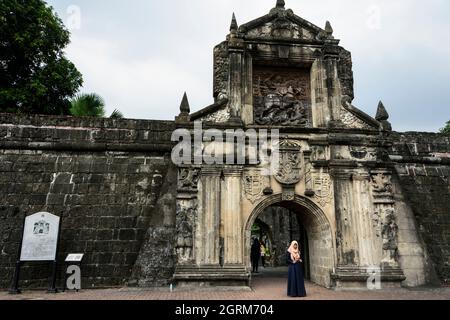 Donna musulmana di fronte al cancello principale ricostruito di Fort Santiago a Manila, Filippine. Foto Stock