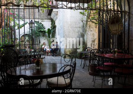 Tre uomini seduti a un tavolo nel patio di una caffetteria a Intramuros, la storica area murata all'interno della città di Manila, Filippine Foto Stock