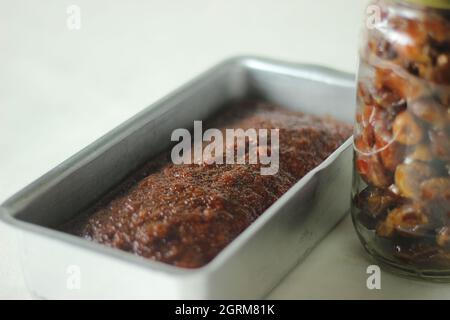 Torta datteri. Un semplice caffè Time Cake con datteri aggiunti alla pastella. Tenuto con in una teglia da forno. Scatto su sfondo bianco Foto Stock