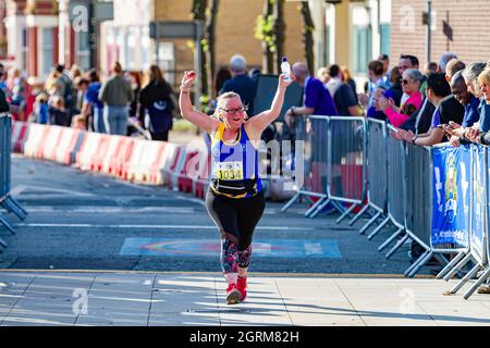 Warrington Running Festival 2021-donna del Warrington Running Club alza le braccia mentre lei attraversa il traguardo Foto Stock