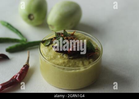 Un condimento a base di pomodoro verde, lenticchie, cipolle, peperoncino e aglio. Popolarmente noto come chutney di pomodoro verde. Scatto su sfondo bianco. Foto Stock