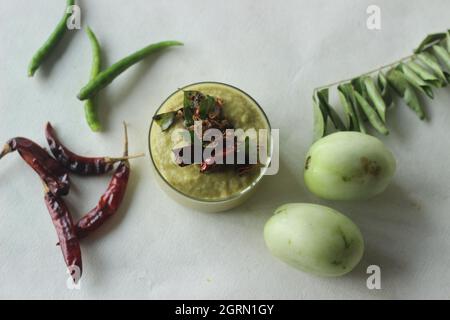 Un condimento a base di pomodoro verde, lenticchie, cipolle, peperoncino e aglio. Popolarmente noto come chutney di pomodoro verde. Scatto su sfondo bianco. Foto Stock