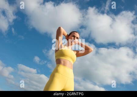 Atleta giovane donna sportiva e in forma con sfondo cielo blu. Il concetto di uno stile di vita e di uno sport sano. Foto Stock