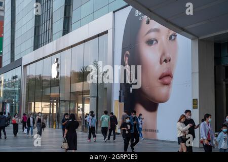 I consumatori cinesi camminano oltre l'etichetta di moda britannica Burberry ad vicino ad un negozio Apple a Pechino, Cina.01-Ott-2021 Foto Stock