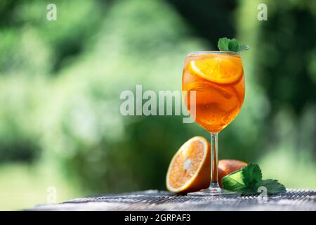 Aperitivo estivo Aperol Spritz aperitivo in vetro originale con arance e rametti di menta su sfondo di legno. Fotografia di cibo e bevande Foto Stock