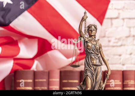 La statua di giustizia Themis o Iustitia, la dea della giustizia cieca contro una bandiera degli Stati Uniti d'America, come un concetto legale. Foto Stock