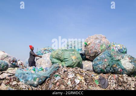 Nakuru, Kenya. 01 ottobre 2021. Una donna è vista smistare i rifiuti delle bottiglie di plastica nel sito di scarico di Gioto per essere portato in un impianto di riciclaggio vicino.il problema crescente dei rifiuti di plastica che finiscono nell'ambiente sta diventando una preoccupazione e gli ambientalisti stanno chiedendo più investimenti nelle infrastrutture per riciclare la plastica per promuovere circolare economia e ridurre l'inquinamento della plastica. Essi chiedono inoltre al governo di introdurre un sistema obbligatorio di deposito e rimborso delle bottiglie (DRS) che darà valore alle bottiglie di plastica per bevande comunemente note come animali da compagnia (polietilentereftalato). Rimborso del deposito sc Foto Stock