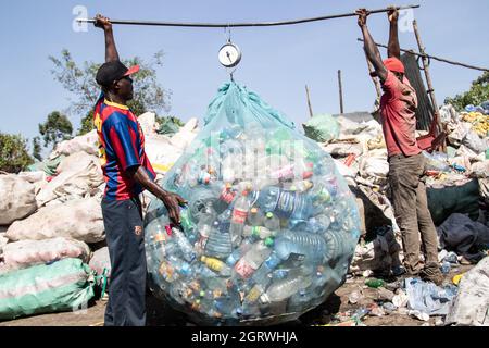 Nakuru, Rift Valley, Kenya. 1 ottobre 2021. I raccoglitori di rifiuti sono visti pesare bottiglie di plastica in un impianto di riciclaggio vicino al sito di scarico Gioto a Nakuru.il problema crescente dei rifiuti di plastica che finiscono nell'ambiente sta diventando una preoccupazione e gli ambientalisti stanno chiedendo maggiori investimenti nelle infrastrutture per riciclare la plastica per promuovere l'economia circolare e ridurre inquinamento plastico. Essi chiedono inoltre al governo di introdurre un sistema obbligatorio di deposito e rimborso delle bottiglie (DRS) che darà valore alle bottiglie di plastica per bevande comunemente note come animali da compagnia (polietilentereftalato). Deposito Cr Foto Stock