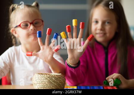 Giù sindrome ragazza e sua sorella più anziana hanno divertimento giocare giochi da tavolo Foto Stock