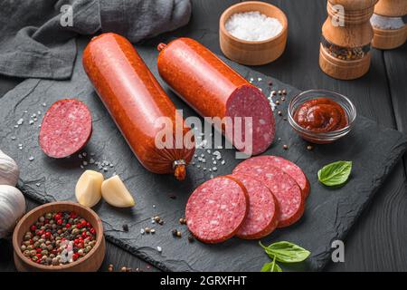 Salsiccia, pezzi tagliati da vicino su uno sfondo scuro. Vista laterale. Foto Stock