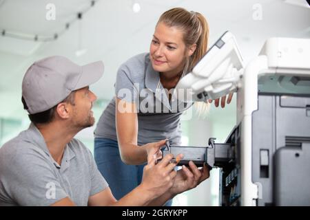 felici due lavoratori e la manutenzione della stampante Foto Stock