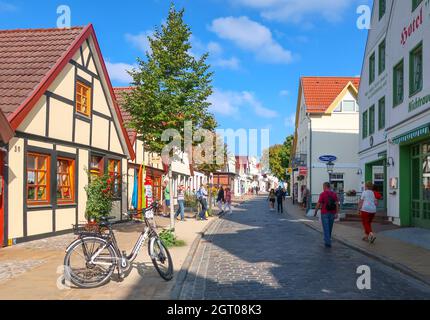La stretta strada acciottolata di negozi, piccole case e caffè nella parte storica di Warnemunde Germania, piena di turisti in estate. Foto Stock