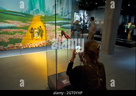 Visitatore che scatta foto iPhone delle pantofole Ruby di Dorothy in una mostra del mago di Oz all'Academy Museum of Motion Pictures, Los Angeles, California Foto Stock