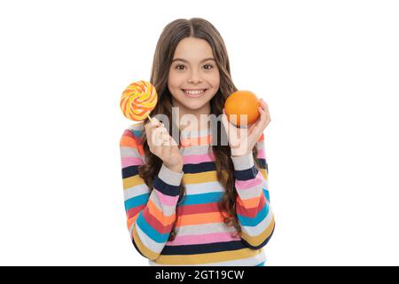 ragazza felice teen in maglione colorato con frutta d'arancia e lecca-lecca isolato su bianco, scelta di cibo Foto Stock