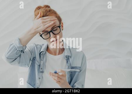 infelice giovane donna triste a causa di infertilità guarda il test di gravidanza con esito negativo Foto Stock