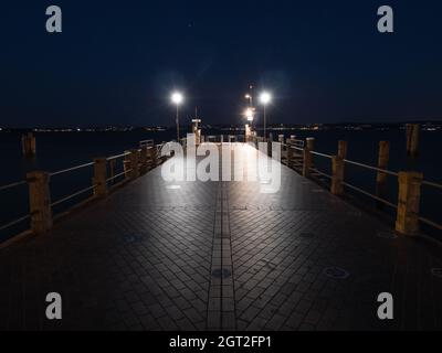 Molo del terminal dei traghetti di Sirmione sul Lago di Garda illuminato di notte Foto Stock