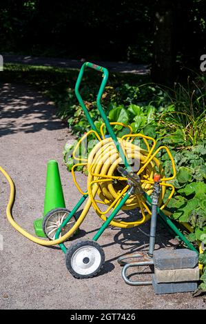 Tubo da giardino giallo su un carrello con ruote. Foto Stock