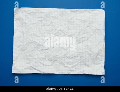 Foglio bianco sgualcito di carta bianca in una gabbia da un notebook scolastico, sfondo blu