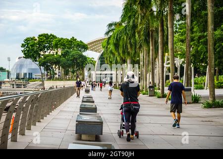 Turisti/locali che si spostano lungo il lato del fiume Singapore verso Marina Bay Sands. Foto Stock