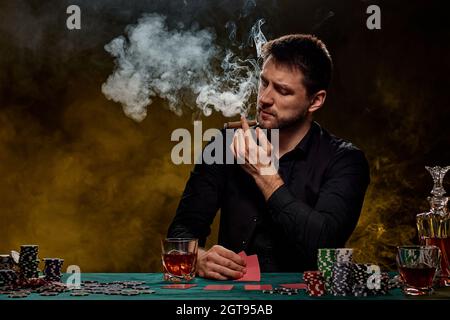 Uomo giocatore di casinò bearded che gioca a poker su tavolo verde Foto Stock