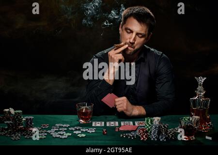 Uomo giocatore di casinò bearded che gioca a poker su tavolo verde Foto Stock