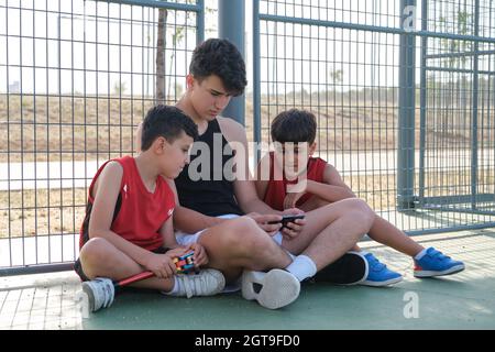 Tre fratelli che guardano qualcosa sullo smartphone. Foto Stock