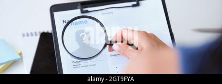 Datore di lavoro che guarda il lavoratore riprendere con ingrandimento closeup di vetro Foto Stock