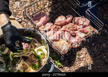 Cook stende cubetti di carne marinata di tacchino in griglia metallica. Cucina di shashlik, barbecue grill Foto Stock