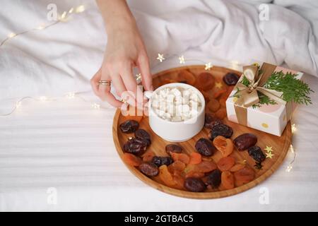 Donna prendere a mano caffè con marshmallows su fogli bianchi con sfondo chiaro. Mattina sorpresa Foto Stock