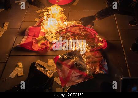 Un dimostratore ha acceso una bandiera cinese e un ritratto di Xi Jinping presidente della Repubblica popolare cinese e leader di Hong Kong Carry Lam durante la protesta contro la repressione del Partito comunista cinese su Hong Kong, Tibet, E Xinjiang nella Giornata Nazionale della Cina al di fuori dell'Ambasciata cinese a Londra. Le comunità di Hongkongers, tibetani e uiguri hanno tenuto un raduno congiunto e marciano a Londra per protestare contro la celebrazione del 72° anniversario della Giornata Nazionale della Repubblica popolare Cinese. Il raduno è iniziato su Piccadilly Circus e ha chiamato il pubblico ad unirsi alla petizione per boicottare la W Foto Stock