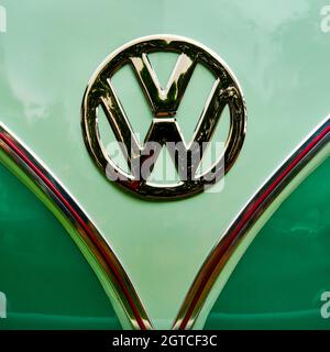 Il logo Volkswagen e il marchio VW di fronte allo storico autobus T1 su sfondo verde a Schöningen, Germania, 12 settembre 2021 Foto Stock