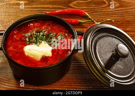 Zuppa tradizionale Ucraina, borsch con panna acida in ciotola metallica su tavola di legno. Ristorante cibo primo piano Foto Stock