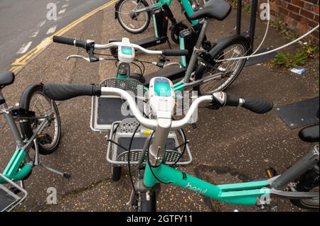 Biciclette elettriche beriliche e scooter elettrici parcheggiati in una baia a norwich con alcuni caduti sopra ostruendo parte del marciapiede Foto Stock