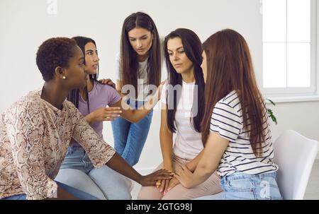 Gruppo di donne che confortano un amico depresso, che parla dei suoi problemi e la sostiene Foto Stock