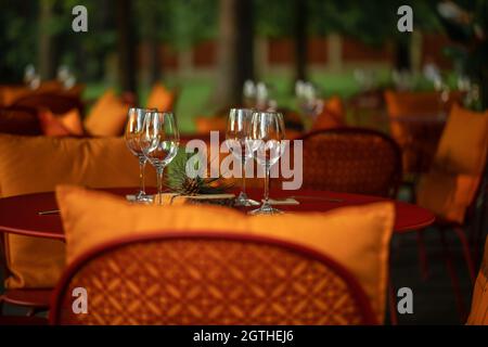 Servito tavolo da pranzo con quattro bicchieri vuoti di vino nella terrazza del ristorante in legno di pino Foto Stock